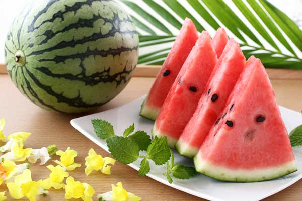 丸いすいかとスライスされた数切れの画像