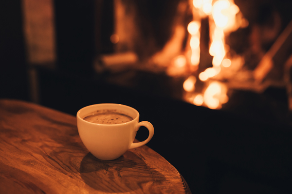 暖炉と木の机の上のココアの入ったマグカップ画像